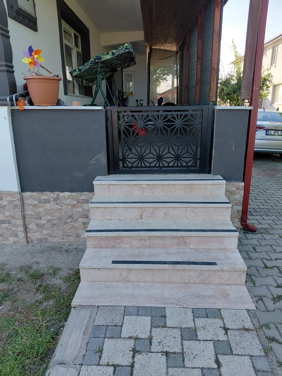 Giriş basamaklarının üstünde geometrik desenli metal bahçe kapısı